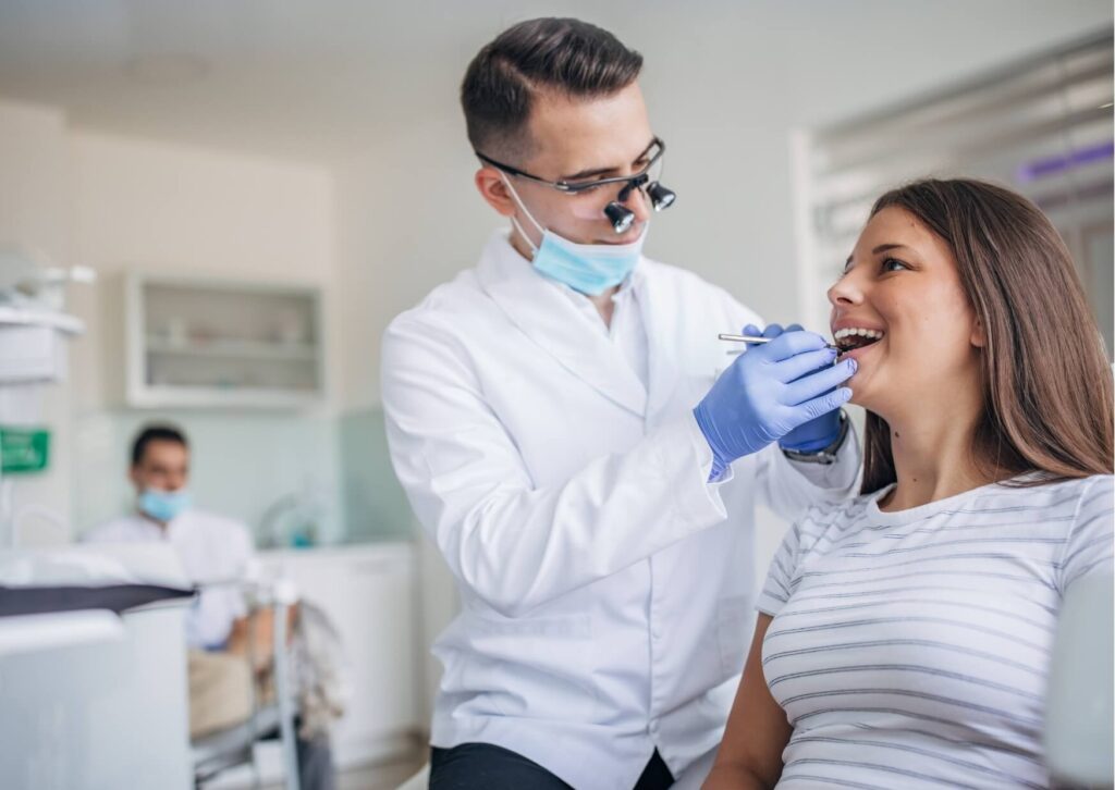 Dentist examining a patient during a dental implant consultation, discussing treatment needs and factors that may affect the overall cost of dental implants.