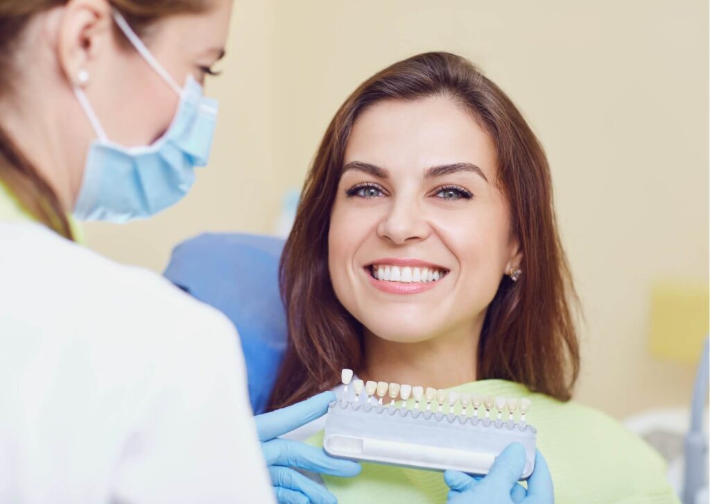 Dentist discussing expected teeth whitening strips effectiveness using a tooth shade guide during a cosmetic dental consultation.