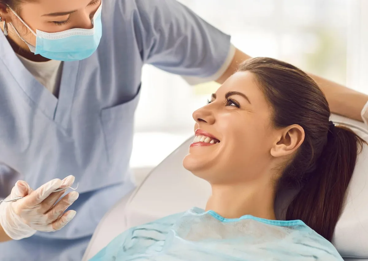 Smiling patient in a dental chair consulting with a dentist about porcelain veneers and their long-term durability.